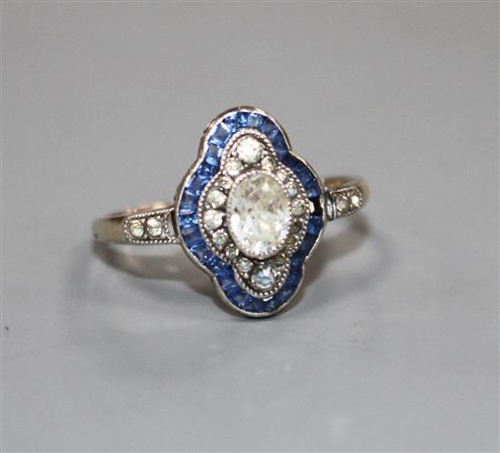 A mid 20th century yellow metal (stamped 9ct?, blue and white paste set quatrefoil shaped ring, size P, gross 2.6 grams.